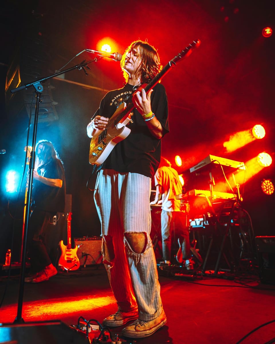 Flipturn. A guitarist in ripped jeans sings on a stage bathed in red light.