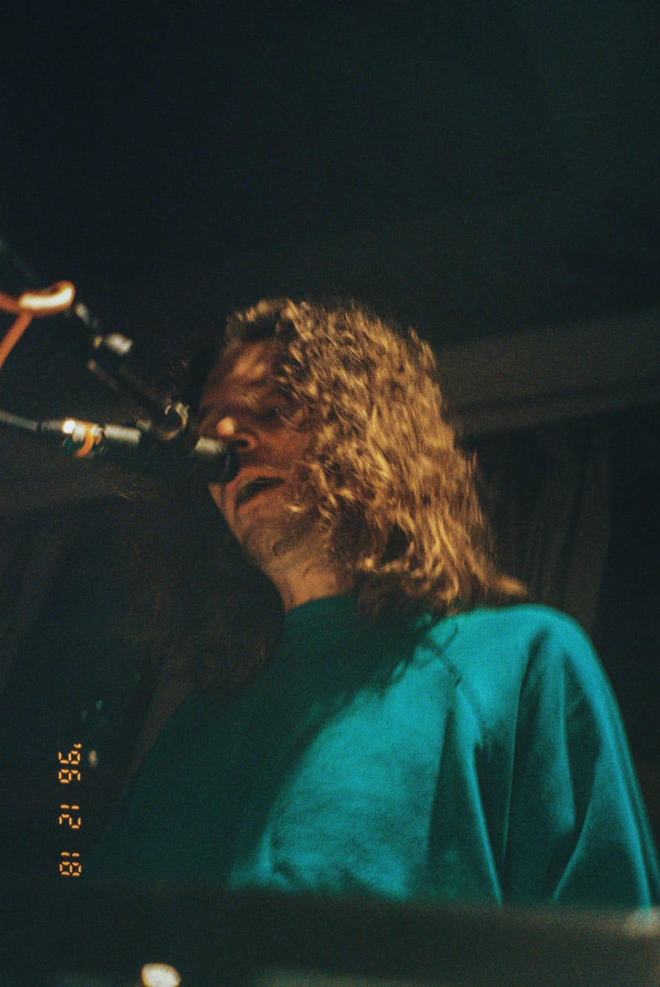 Mo Lowda and the Humble. A curly-haired singer in a teal sweatshirt sings into a microphone, shot from below.