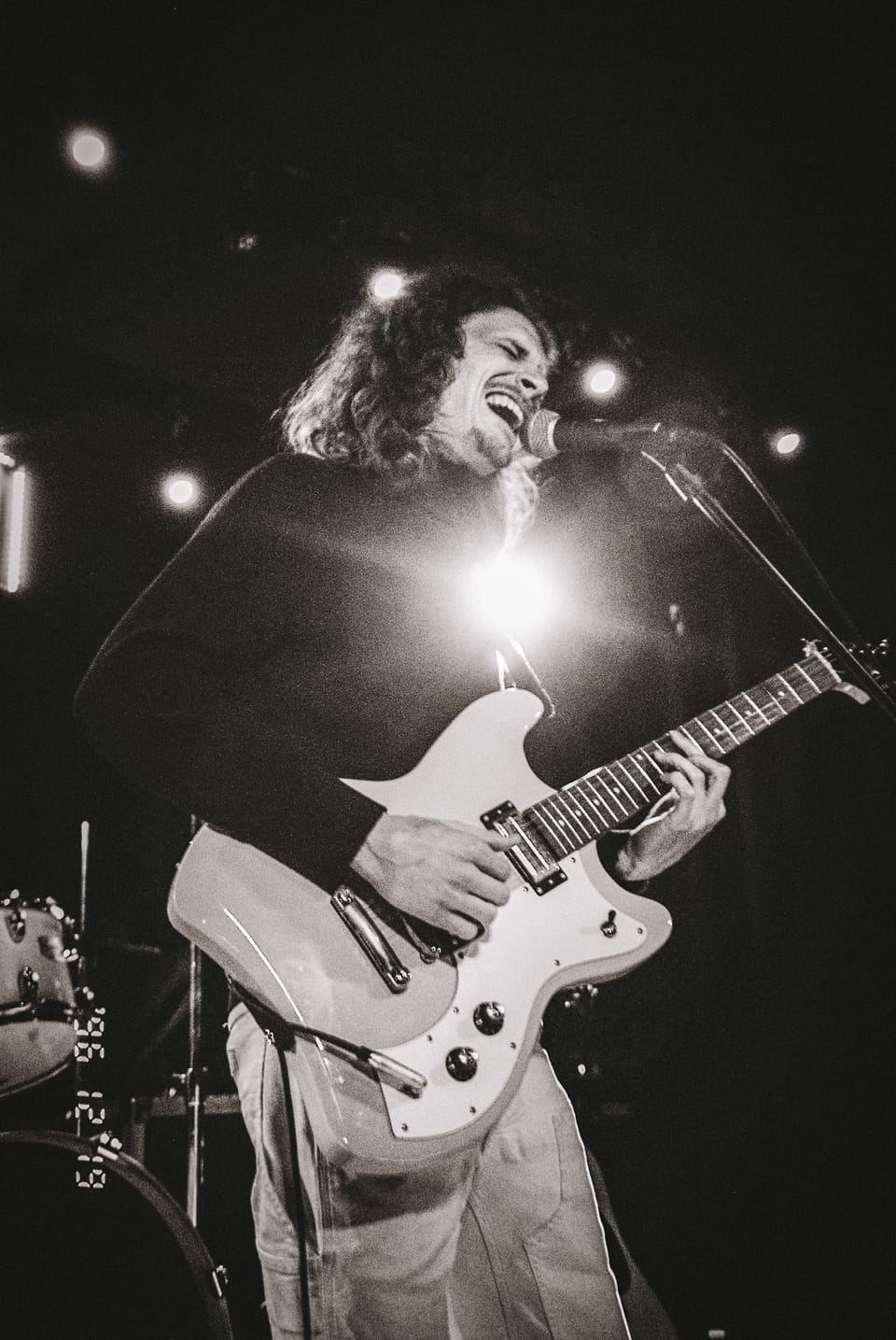 Mo Lowda and the Humble. A black and white photo of a singer-guitarist under a bright spotlight.