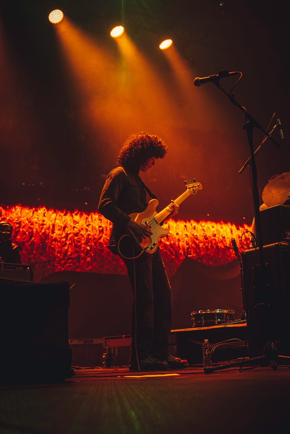 Tyler Childers. A guitarist plays in front of a glowing red crowd, seen from the side of the stage.