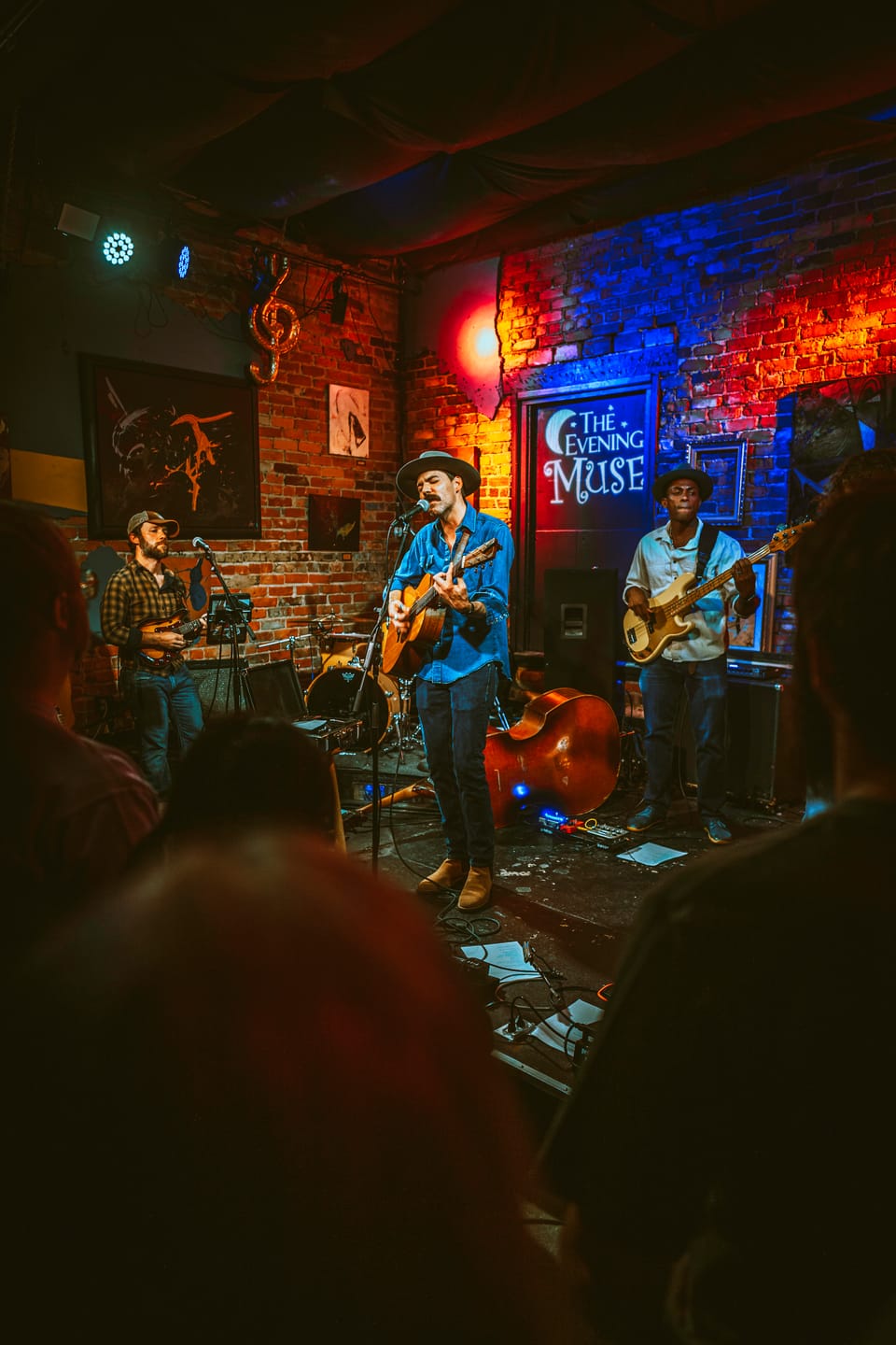 Time Sawyer. A band plays on a small brick-walled stage with an upright bass, seen from behind the crowd.