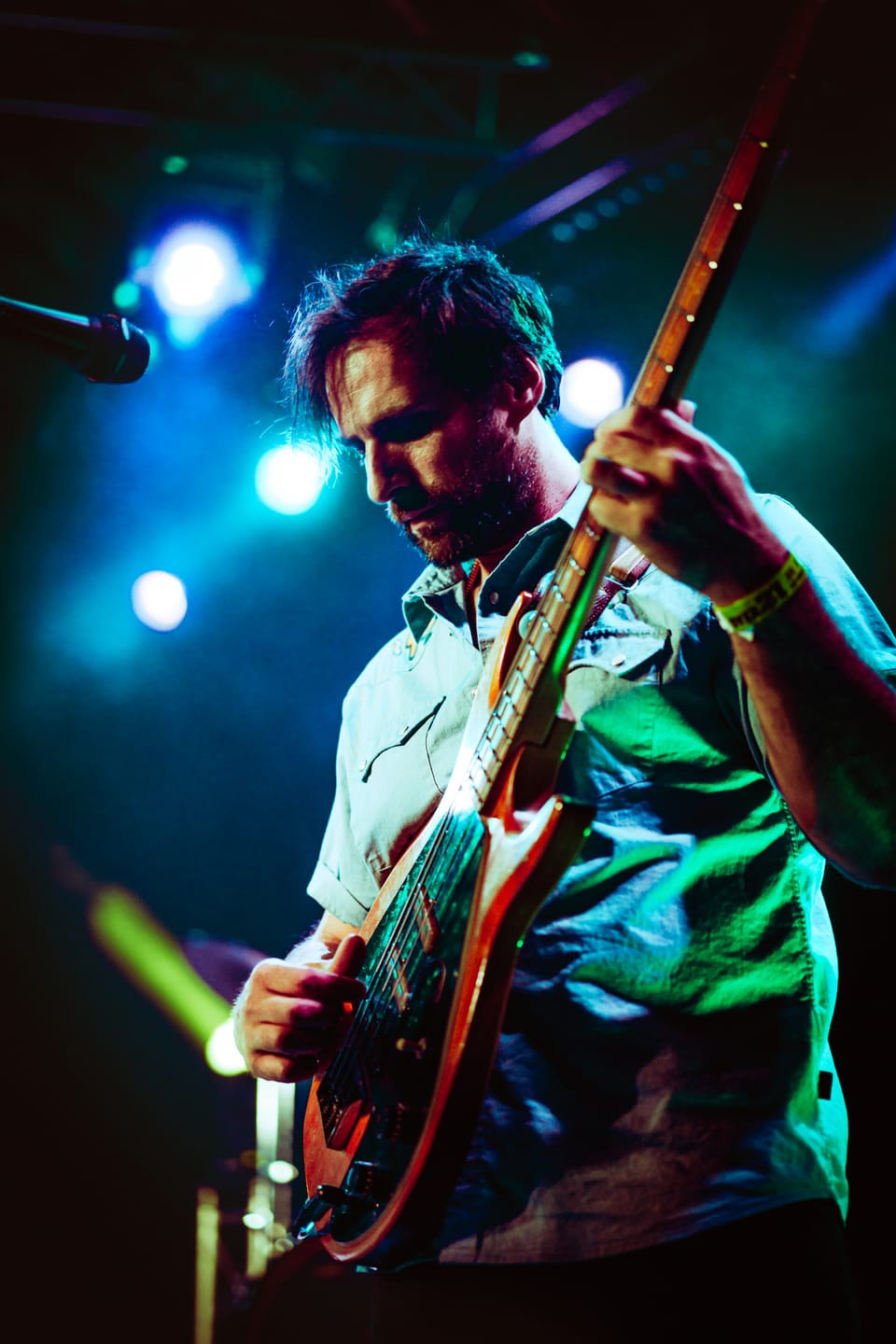 Mo Lowda and the Humble. A guitarist looks down at his red guitar under blue and green stage lights.