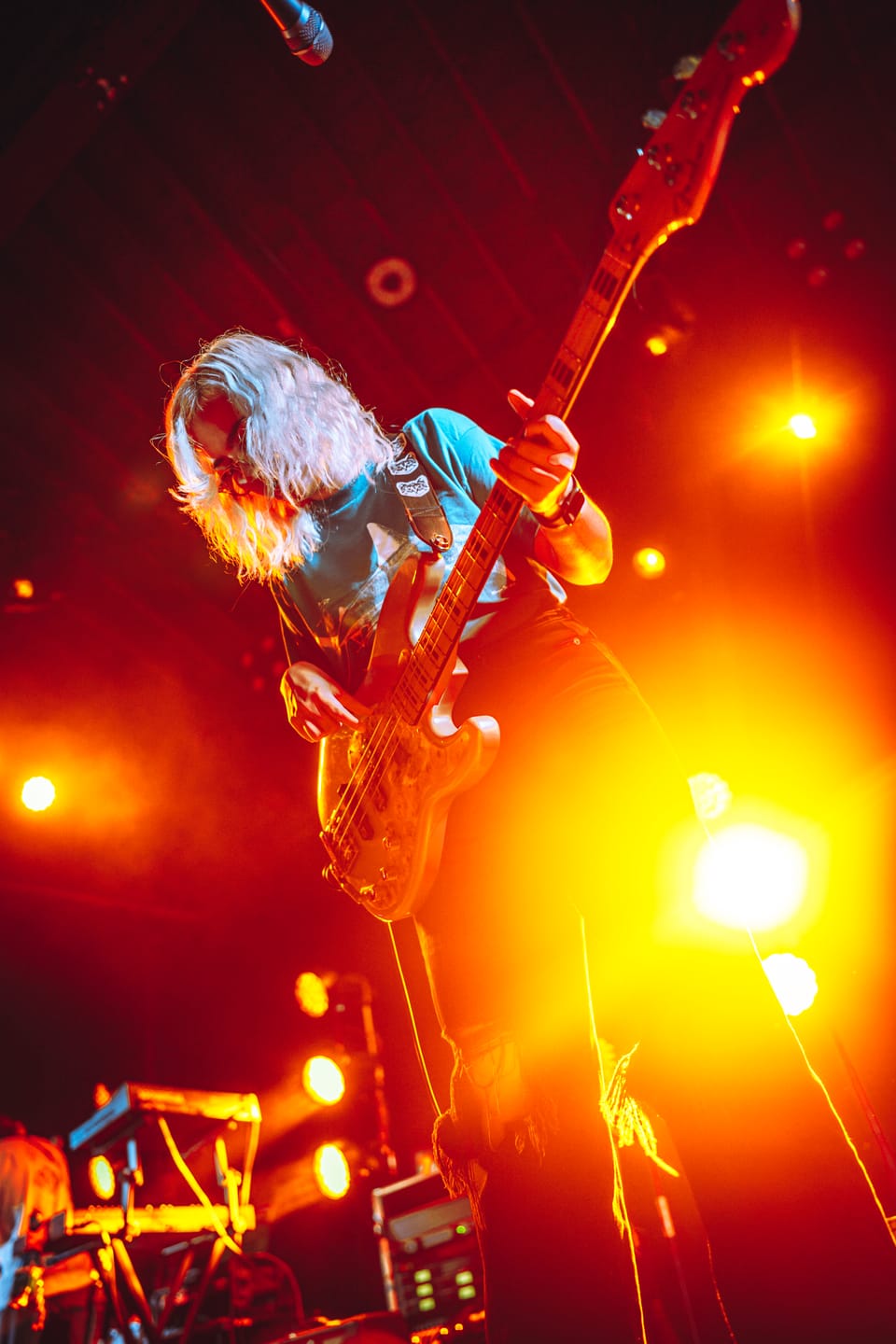 Flipturn. A long-haired guitarist plays under glowing orange lights, seen from below.