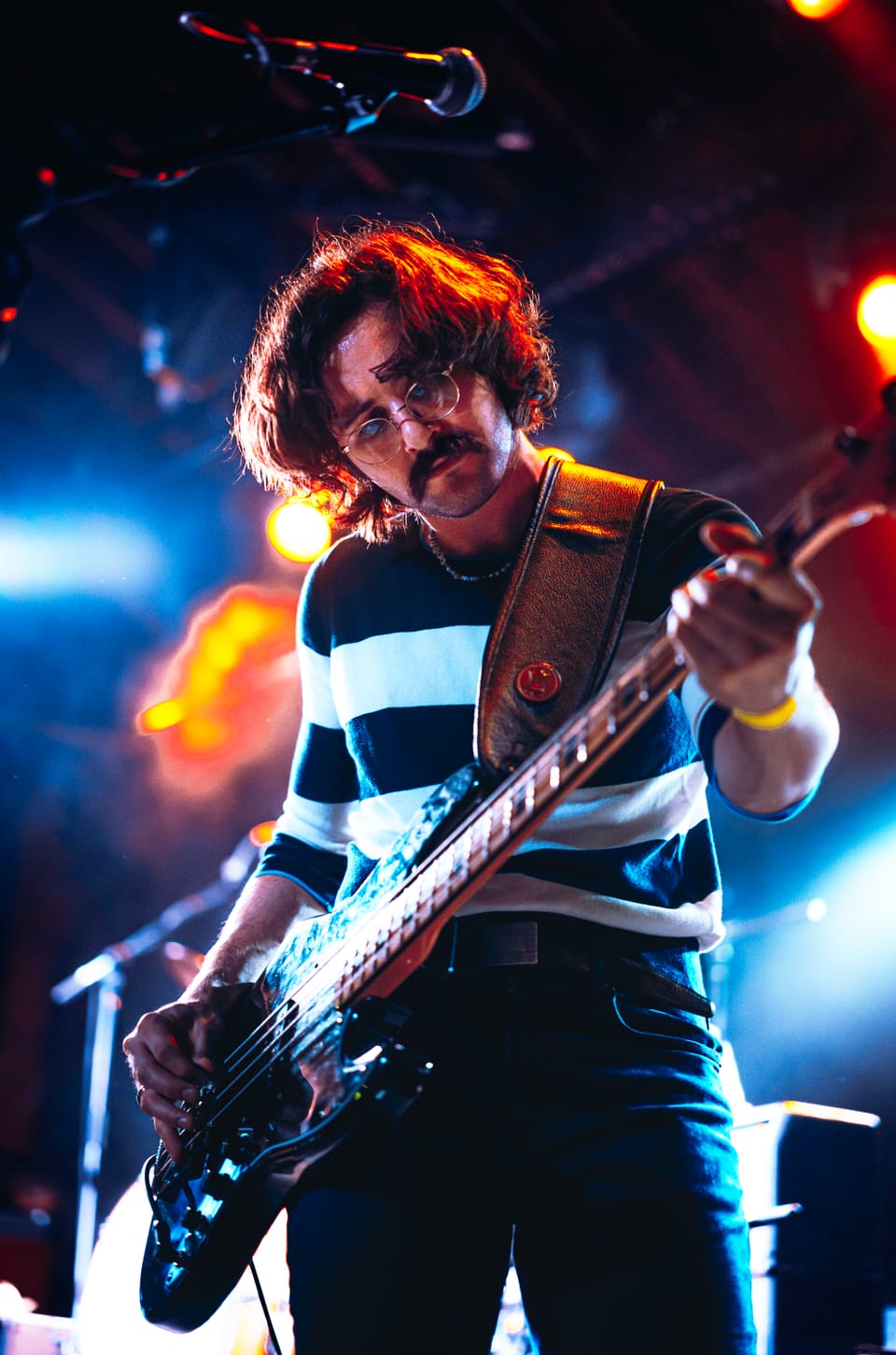 Flipturn. A bassist in a striped shirt plays under blue and orange lights.