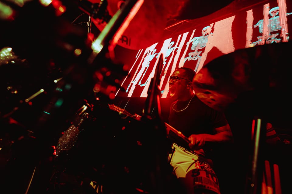 An abstract, red-lit shot of stage gear and a bright screen, blurred and tilted.