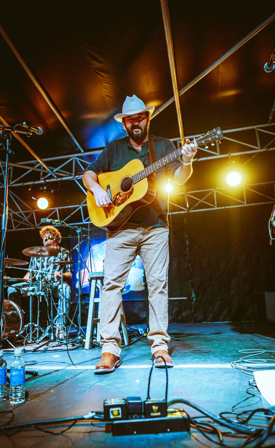 Town Mountain. A guitarist in a white cowboy hat plays acoustic guitar on a stage under a metal truss.
